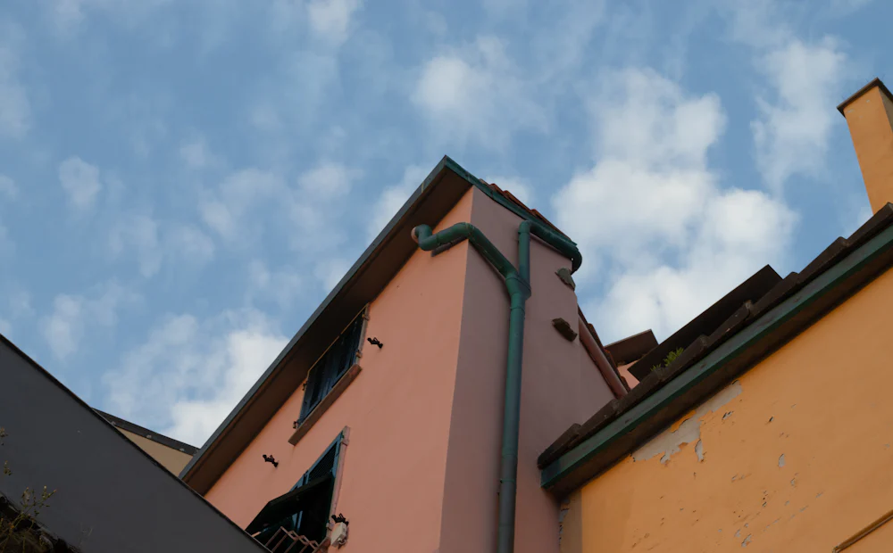 Esquina de una fachada con su canalón y bajante vistos desde abajo